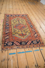 Angled perspective of an antique Heriz rug highlighting its bold central medallion and navy border.