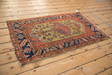 Full perspective view of an antique Persian Heriz rug with its ochre field and geometric medallion.