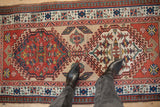 Antique Serab runner's brick red field with ivory, navy, and subtle green germinating floral motifs.