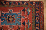 Upper corner of vintage Karaja rug, brick red field, sky blue medallion edge, and patterned vine borders.
