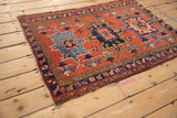 Vintage Karaja rug corner, detailing navy blue border with floral vines and brick red field.