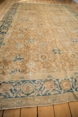 Angled view across the Safavid-inspired field of a distressed antique gold Persian carpet.