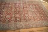 Angled view of a distressed vintage Mahal carpet showing its low pile and floral field.
