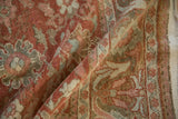 Textured close-up of a vintage Mahal carpet with low, even wear across its raspberry red and slate blue floral motifs.