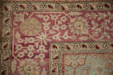 Antique distressed Yezd carpet corner, dusty magenta field, ivory, and copper border motifs.