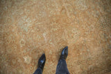Distressed Tabriz rug texture showing faded gold, brown, and sea foam green floral motifs.