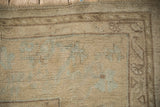 Muted beige border and soft powder blue motifs on a distressed vintage Oushak carpet.