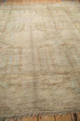 Distressed Oushak carpet pile revealing muted ivory, beige, and faint powder blue curvilinear motifs.