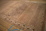 Angled view showing heavy color variation and low pile texture on a distressed vintage Malayer carpet.