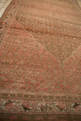A distressed Malayer carpet's corner, showing the stepped spandrel against the worn Herati field pattern.