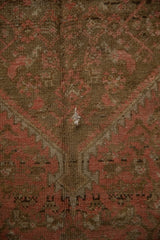 Exposed foundation threads on a distressed Malayer rug with blush and brown geometric patterns.