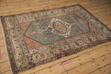 Distressed Hamadan rug corner, faded terracotta, time-softened blues, and ornate floral borders.