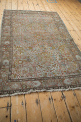Faded Gol Ferang pattern on a distressed Sarouk rug's lower border with worn fringe.