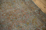 Distressed Sarouk rug's worn pile, dusty blue, terracotta, and green gold floral vines.