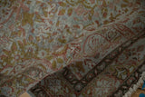 Distressed Sarouk rug's worn pile, revealing muted dusty blue, rose, and green-gold florals.