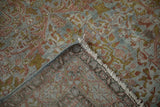 Distressed Sarouk rug corner revealing low pile, woven foundation, and soft Gol Ferang floral patterns.