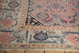 Distressed antique Malayer rug corner with geometric vinery and blush, navy floral border.