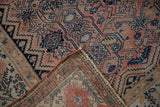Distressed Malayer rug corner revealing geometric floral pattern, textural pile, and secure selvage.