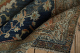 The soft, worn pile of a folded vintage Persian rug in deep sapphire blue and rust tones.