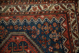Close-up of the antique Afshar rug's colorful serrated leaf border and sapphire blue field.