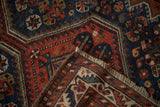 Folded corner of an antique Afshar rug revealing its hand-knotted foundation and short fringe.