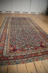 Angled view of an antique Malayer carpet highlighting the blue abrashes in its classic Herati design.