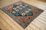 Detailed corner of vintage Mehriban rug, with geometric borders and teal motifs on rust field.