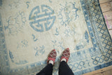 Roundel medallion and floral vines in powder blue on the distressed ivory field of a Peking carpet.