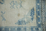 Softly distressed ivory wool pile showing a blue butterfly corner and geometric border.