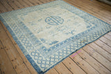Worn corner of a Peking rug showing distressed blue trellis and meander patterned borders.