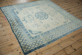 A corner perspective of the antique distressed Peking carpet's faded blue and ivory design.