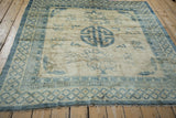 An antique Peking square carpet with a distressed ivory and sky blue design shown from a high angle.