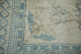 Close view of the pearl and geometric motifs in the soft blue border of a distressed Peking rug.