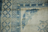 Detail of the blue trellis, key, and pearl motif borders on a distressed antique Peking carpet.