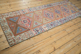 Corner of antique Northwest Persian rug with geometric stepped spandrel in beige, red, blue.