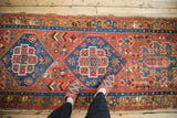 A view along the antique Persian runner highlighting its central indigo blue hexagonal medallion.