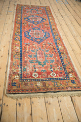 Full length of an antique Persian runner from an angle, showing its hexagonal medallions on a brick red field.