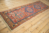 Angled perspective of an antique Northwest Persian runner with geometric medallions and a brick red field.
