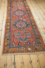 Antique Persian runner with brick red and indigo medallions laid out at a long angle.
