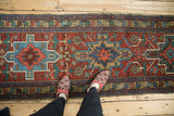 Geometric vintage Heriz runner features inverted medallions and serrated leaves in red and blue.