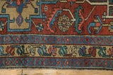 Heriz rug runner's layered borders with sky blue, cherry red, gold geometric patterns and selvage wear.