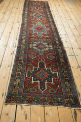 Vintage Heriz runner's corner, geometric serrated leaves and patterned blue, red, and gold borders.