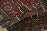 Vintage Heriz runner rolled, showing geometric motifs in cherry red, emerald green, sky blue.
