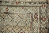 Distressed vintage Caucasian rug detail with textured diamond field and geometric border.