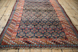 Corner detail of vintage Kurdish rug showing blue and red diagonal and pawn motif borders.