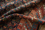 Vibrant henna plant motif field meeting geometric pawn border on a vintage Kurdish rug.