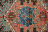 Vintage Heriz rug's sapphire blue geometric pattern, ruby red stylized pomegranate blossoms.