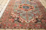 Textured ruby red border and geometric motifs on the sky blue field of a vintage Heriz rug.