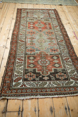 Distressed Malayer rug runner detail with rust, time-softened silver medallion, and serrated border.