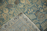 The corner of a vintage Tabriz rug folded over to show its hand-knotted weave and foundation.